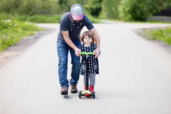 Father teaching his adorable toddler daughter to ride kick scoot — Stock Photo, Image