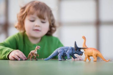 bir oyuncak dinozor ile oynayan yürümeye başlayan çocuk