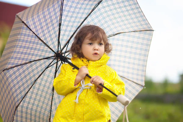 Niña pequeña con abrigo impermeable amarillo con umrel a cuadros — Foto de Stock