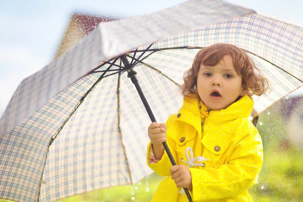 Niña pequeña con abrigo impermeable amarillo con umbre acariciado — Foto de Stock