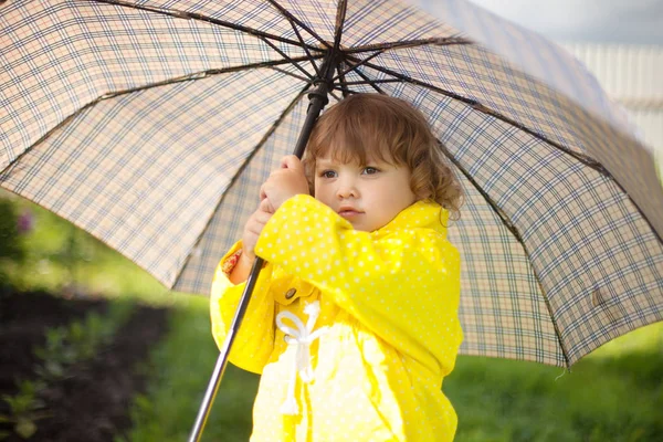 Niña pequeña con abrigo impermeable amarillo con umbrel acariciado — Foto de Stock