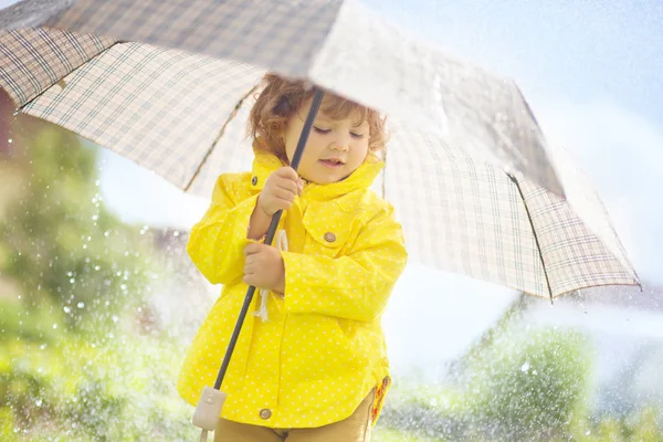 Cute toddler girl wearing yellow waterproof coat and boots with — Stock Photo, Image