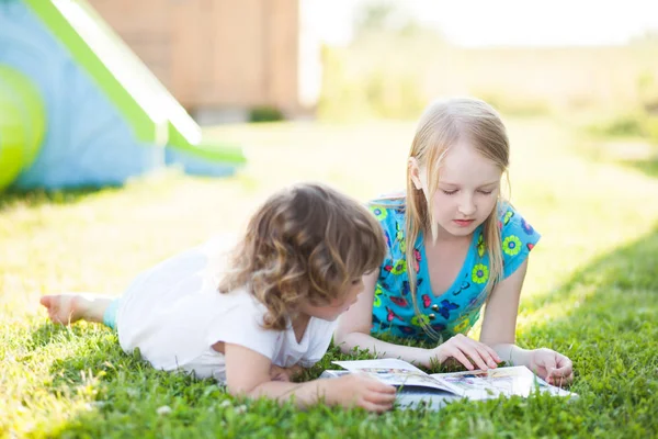 Dos hermanas pequeñas leyendo al aire libre en el día de verano — Foto de Stock