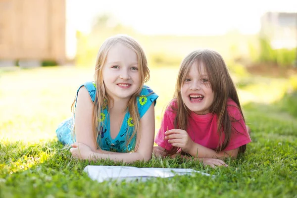 Две младшие сестры читают на свежем воздухе, веселятся — стоковое фото