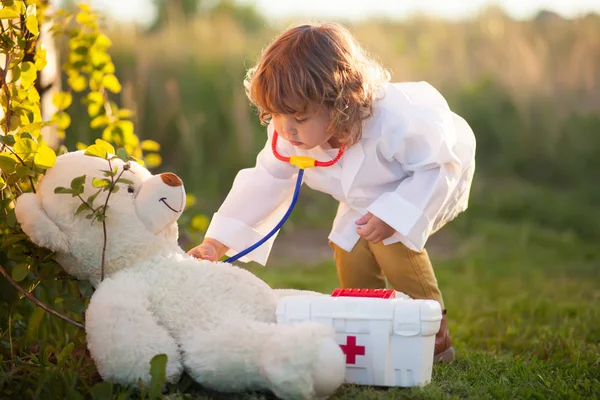 Bambino ragazza giocare medico con orsacchiotto putdoors Foto Stock Royalty Free