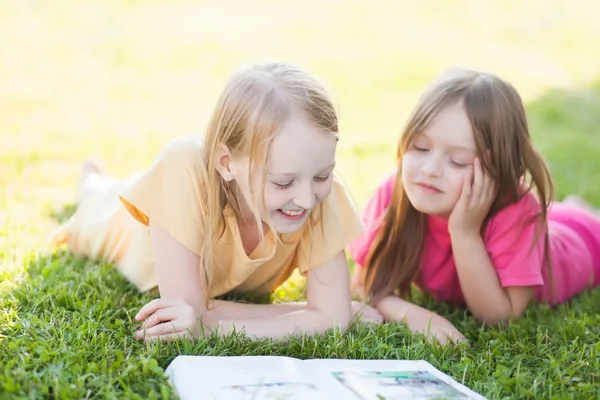 Dos hermanas leyendo al aire libre, divirtiéndose — Foto de Stock