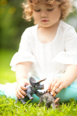 bir oyuncak dinozor ile oynayan yürümeye başlayan çocuk