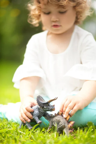 Kleinkind spielt mit einem Spielzeug-Dinosaurier — Stockfoto
