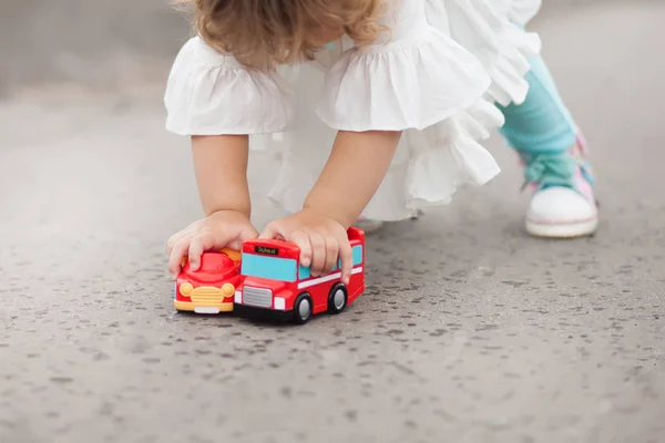 Menina brincando com carros de brinquedo ao ar livre — Fotografia de Stock