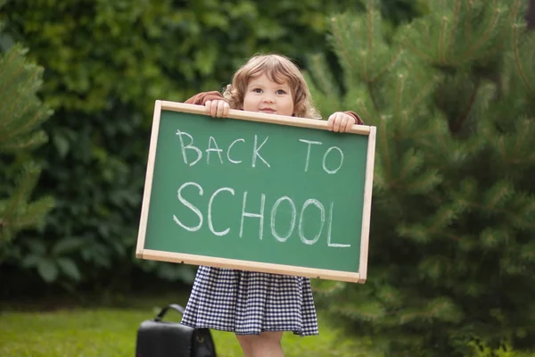 Geri okul metin blackboar ile sevimli gülümseyen yürümeye başlayan çocuk kız