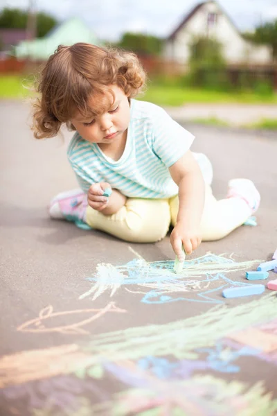 Niedliche Kleinkind Mädchen Zeichnung mit einem Stück Farbkreide Stockfoto