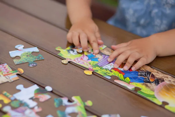 Kind spielt mit Puzzle. Kinderhände in Nahaufnahme — Stockfoto