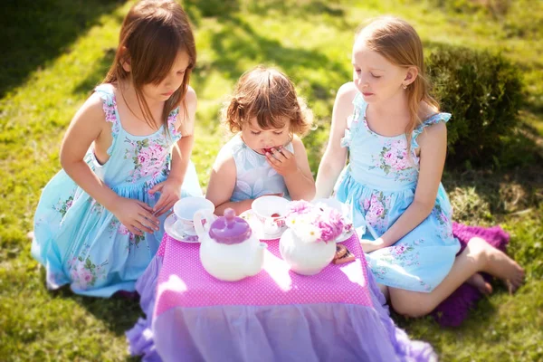 Three sisters playing tea party outdoors
