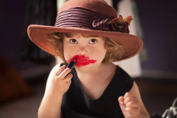 Niña probando el lápiz labial de mamá. Concepto de crecimiento Imagen De Stock