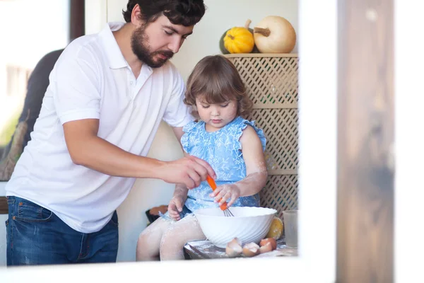 Father cooking cake with his cute little daughter