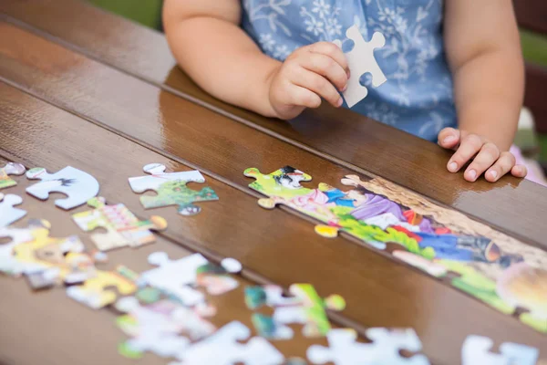 Kind spielt mit Puzzle. Kinderhände in Nahaufnahme — Stockfoto