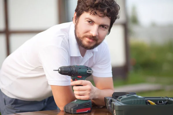 handsome bearded man holding electric drill