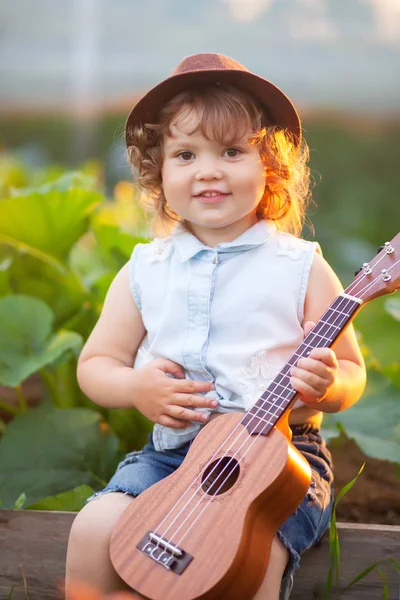 Küçük kız oyun ukulele açık havada