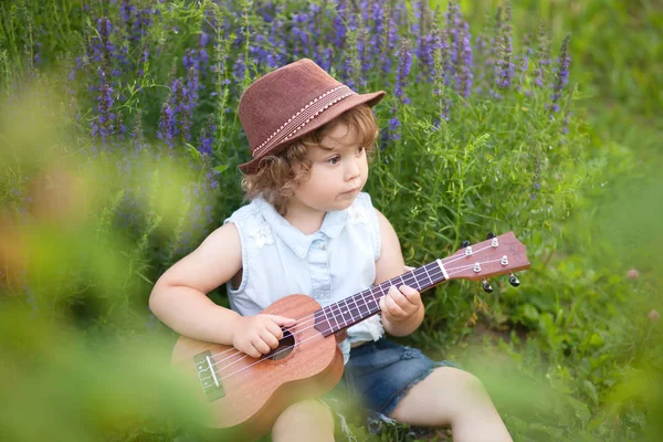 Маленькая девочка играет на укулеле на открытом воздухе — стоковое фото