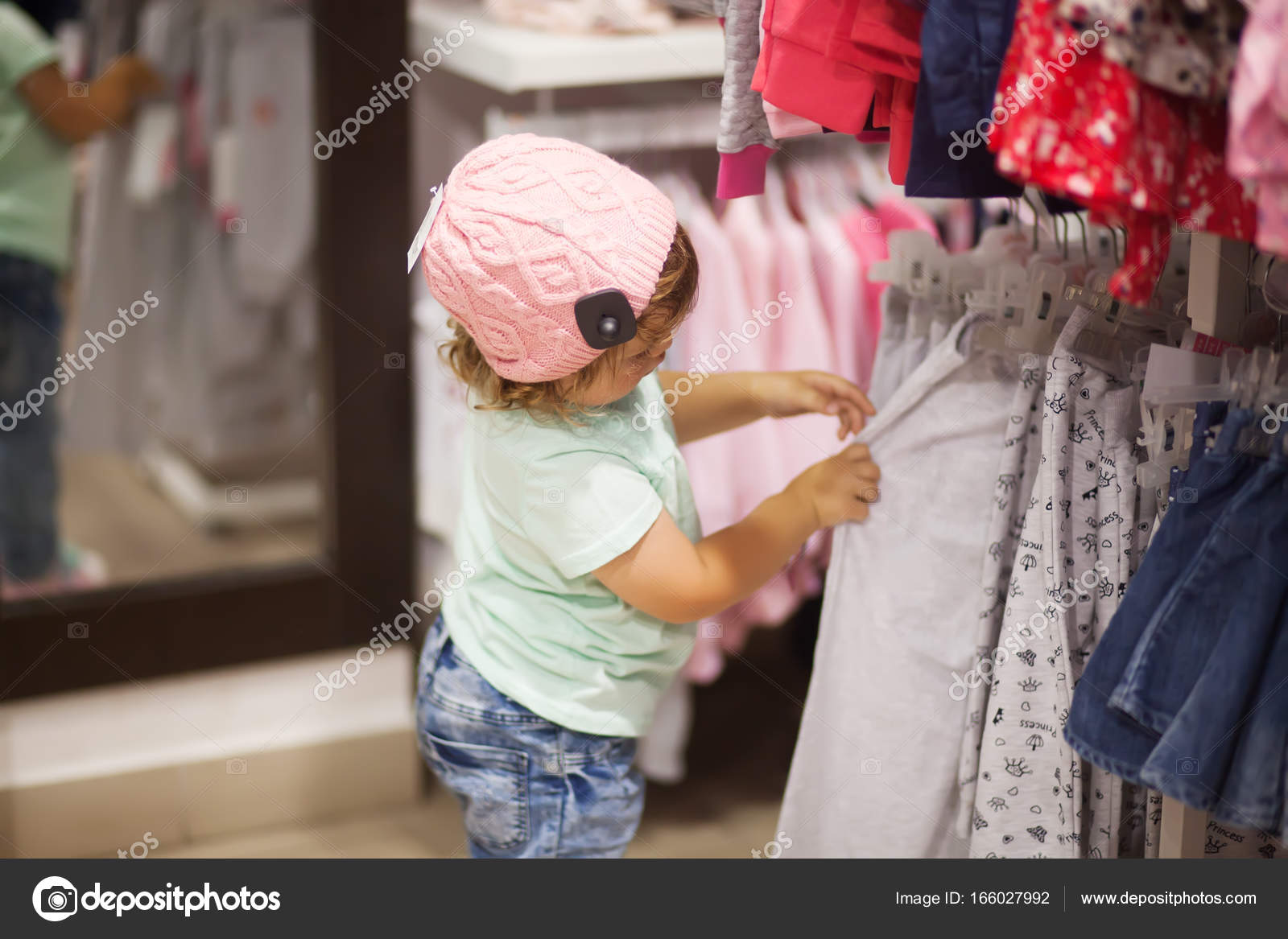 Cute little girl choosing clothes in the shop Stock Photo by ©Alinsssa