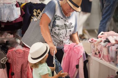 Sevimli küçük kız ve büyük annesi dükkanda giysiler seçmek