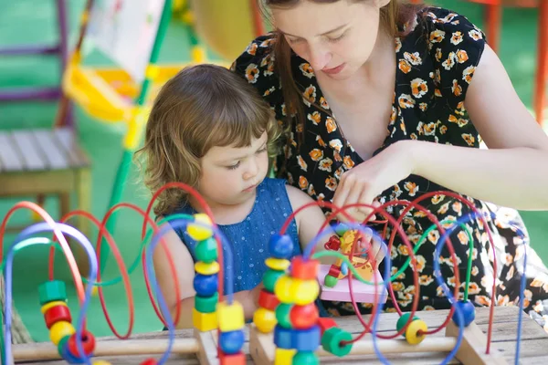 Petite fille et mère jouer avec jouet éducatif Image En Vente