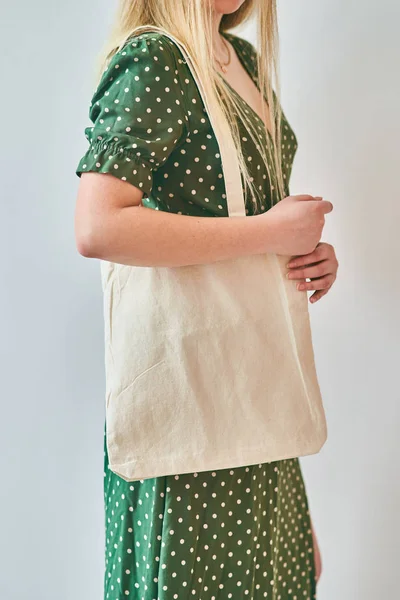 Una chica está sosteniendo bolsa de algodón eco tote en blanco, maqueta de diseño . — Foto de Stock