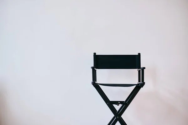 Black director\'s chair against a white wall