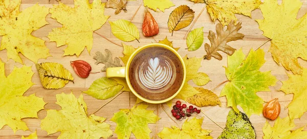 Composición plana de otoño con marco de corona de hojas secas y taza de café con leche sobre fondo de madera . — Foto de Stock
