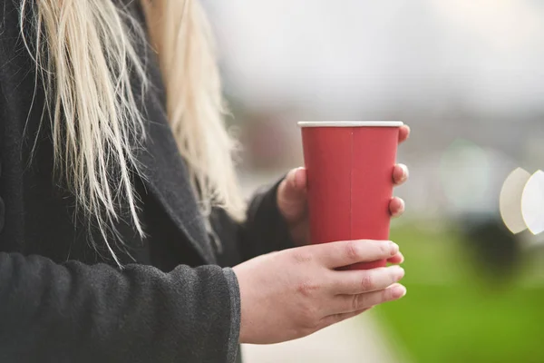 Une jeune fille tient une tasse de café dans ses mains . — Photo