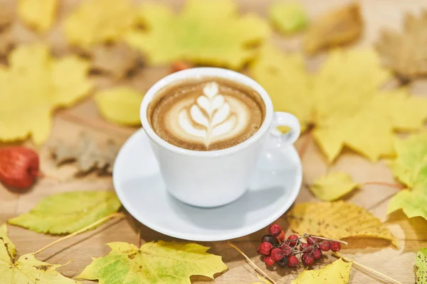 Composición plana de otoño con marco de corona de hojas secas y taza de café con leche sobre fondo de madera . — Foto de Stock