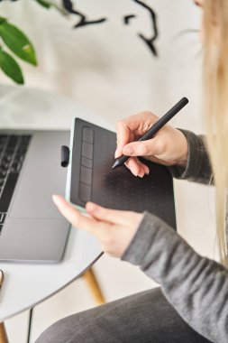 Genç bir kız grafik tabletine resim çiziyor. Freelancer bir kafede çalışıyor.