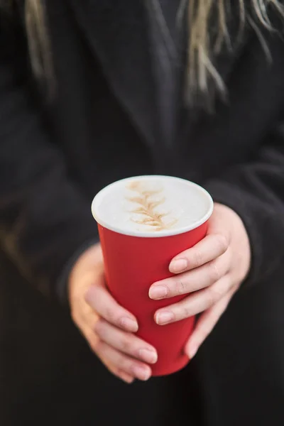 Une jeune fille tient une tasse de café dans ses mains . — Photo