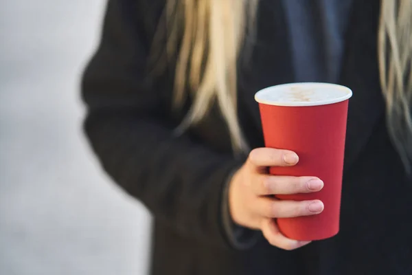 Une jeune fille tient une tasse de café dans ses mains . — Photo