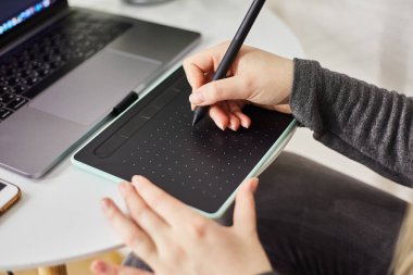 Kaliningrad, Rusya - 27 Ekim 2019: Genç bir kız grafik tabletine resim çiziyor. Freelancer bir kafede çalışıyor.