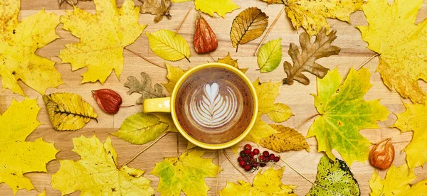 Composición plana de otoño con marco de corona de hojas secas y taza de café con leche sobre fondo de madera . — Foto de Stock