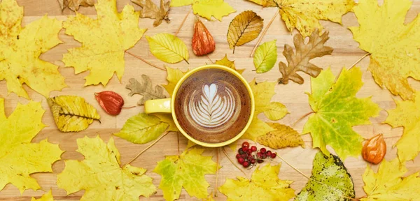 Composición plana de otoño con marco de corona de hojas secas y taza de café con leche sobre fondo de madera . — Foto de Stock