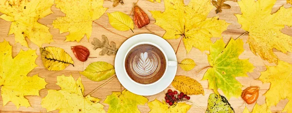 Composición plana de otoño con marco de corona de hojas secas y taza de café con leche sobre fondo de madera . — Foto de Stock