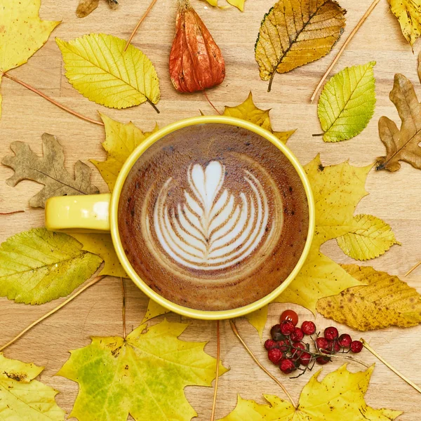 Composición plana de otoño con marco de corona de hojas secas y taza de café con leche sobre fondo de madera . — Foto de Stock