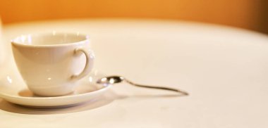 Çay tabağı ve kaşıkla beyaz kahve fincanı.