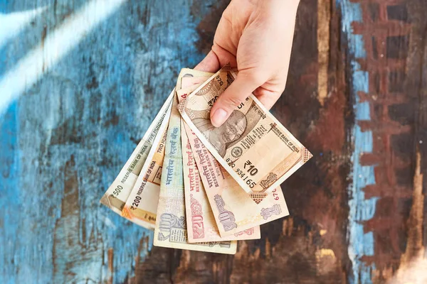 The girl holds Indian rupees in denominations of 10, 20, 100, 500. Indian money on a white background. — Stock Photo, Image