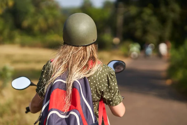Ein Mädchen im grünen Kleid fährt einen Motorroller. — Stockfoto