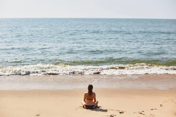 Una joven se está relajando en la playa. La chica practica yoga — Foto de Stock