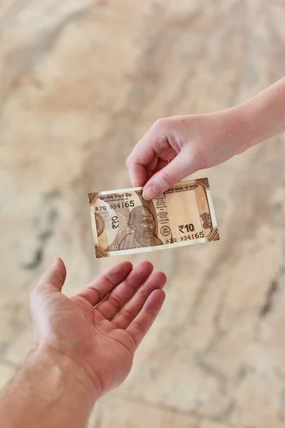 A young girl pays Indian rupees. The girl pays the man.