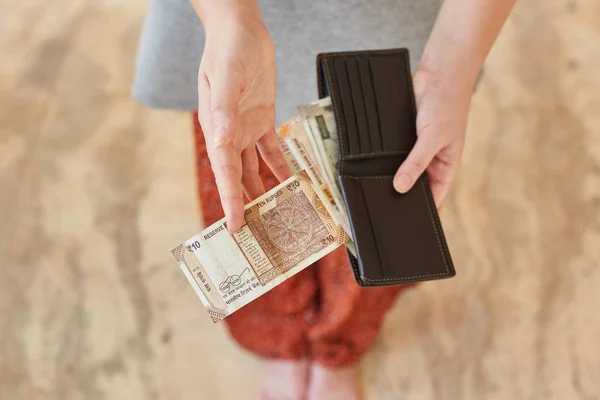 Дівчинка тримає гаманець і платить 10 індійських рупій. — стокове фото