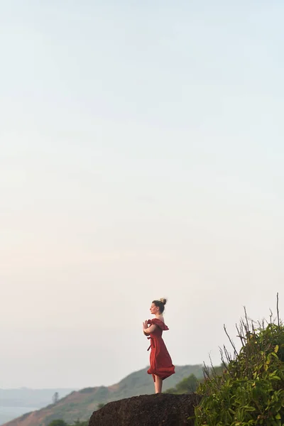 Junges Mädchen praktiziert Yoga in rotem Kleid auf einem Berg in Indien — Stockfoto