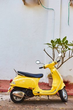 Panaji, Goa, Hindistan - 15 Aralık 2019: Sarı bir scooter beyaz bir duvara park etti. Eyalet başkenti Goa Panaji sokakları
