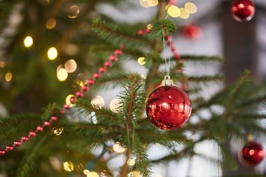 Noel ağacında kırmızı top. Çelenklerle bokeh arka planda Noel oyuncağı.