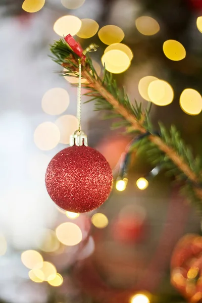 Bola vermelha numa árvore de Natal. Brinquedo de vidro de Natal no fundo bokeh com guirlandas . — Fotografia de Stock