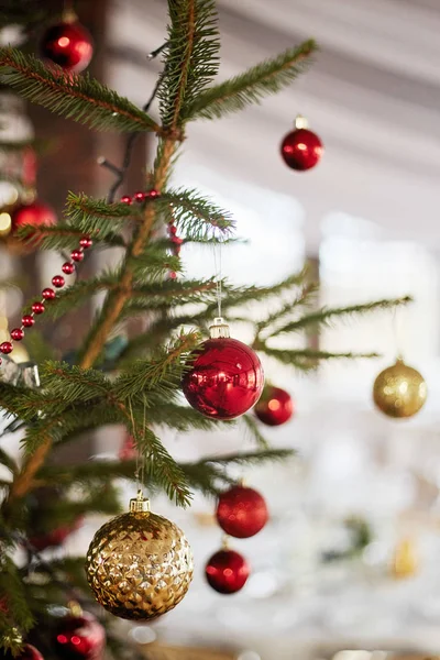 Bolas vermelhas numa árvore de Natal. Brinquedos de vidro de Natal no fundo bokeh com guirlandas . — Fotografia de Stock
